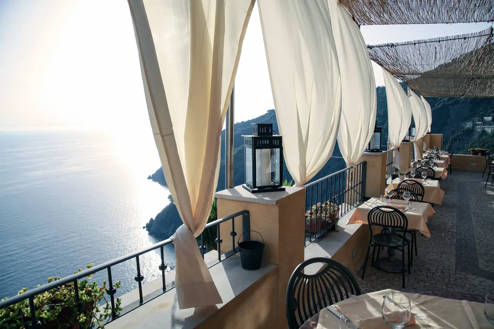Tavoli preparati in veranda con vista mare come riferimento visivo per il caso studio