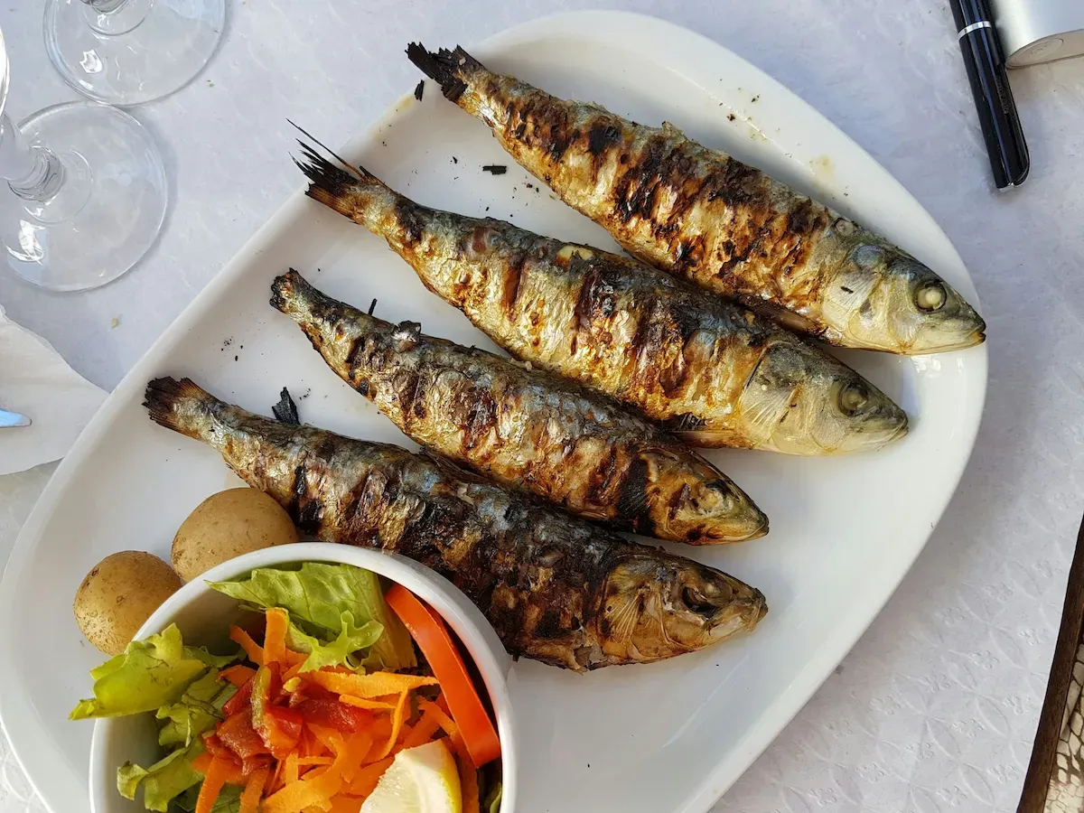 Piatto con pesce alla griglia, insalata e pomodori freschi
