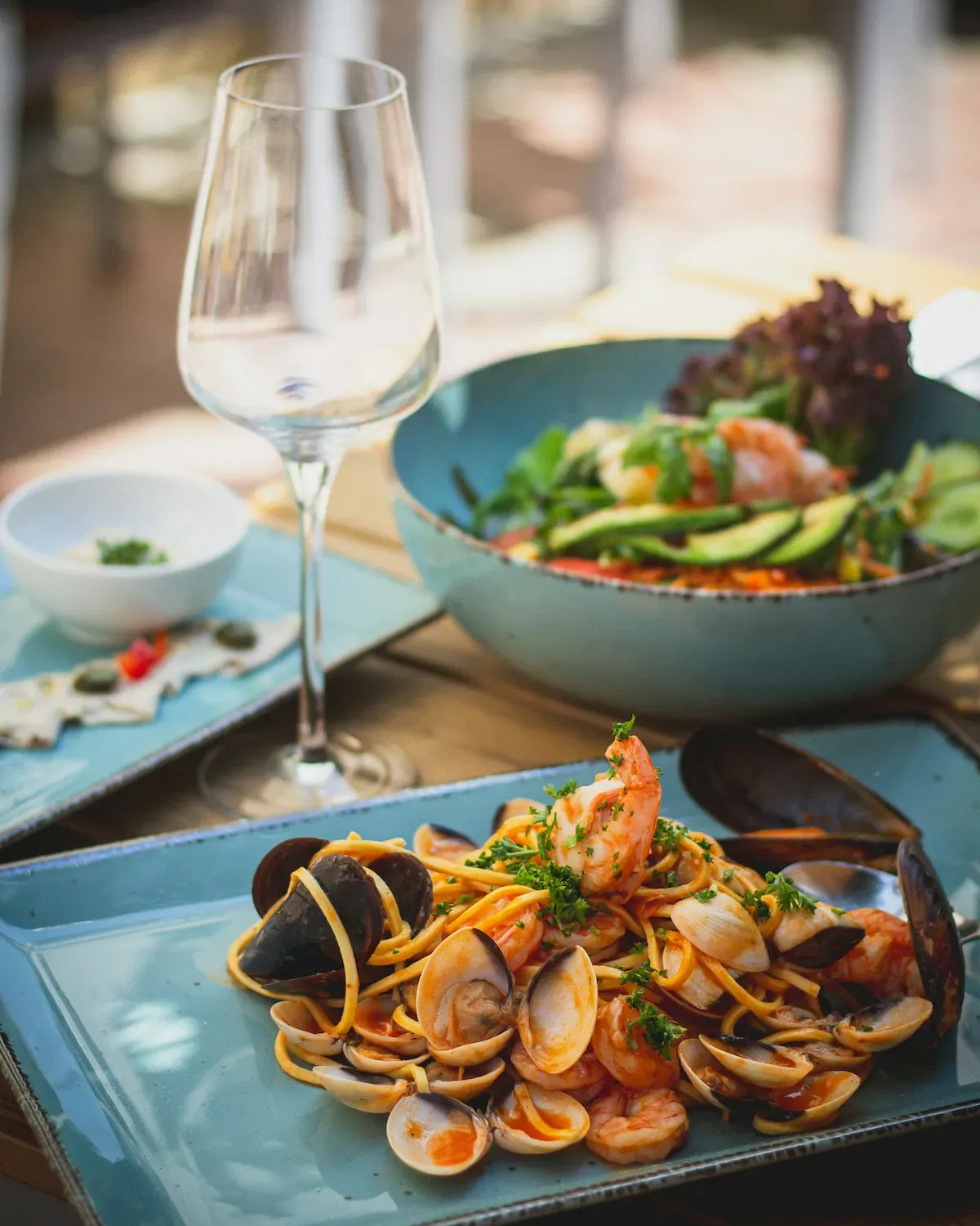 Due piatti di mare e un calice di vino su un tavolo del menu demo Azzurro di Mare