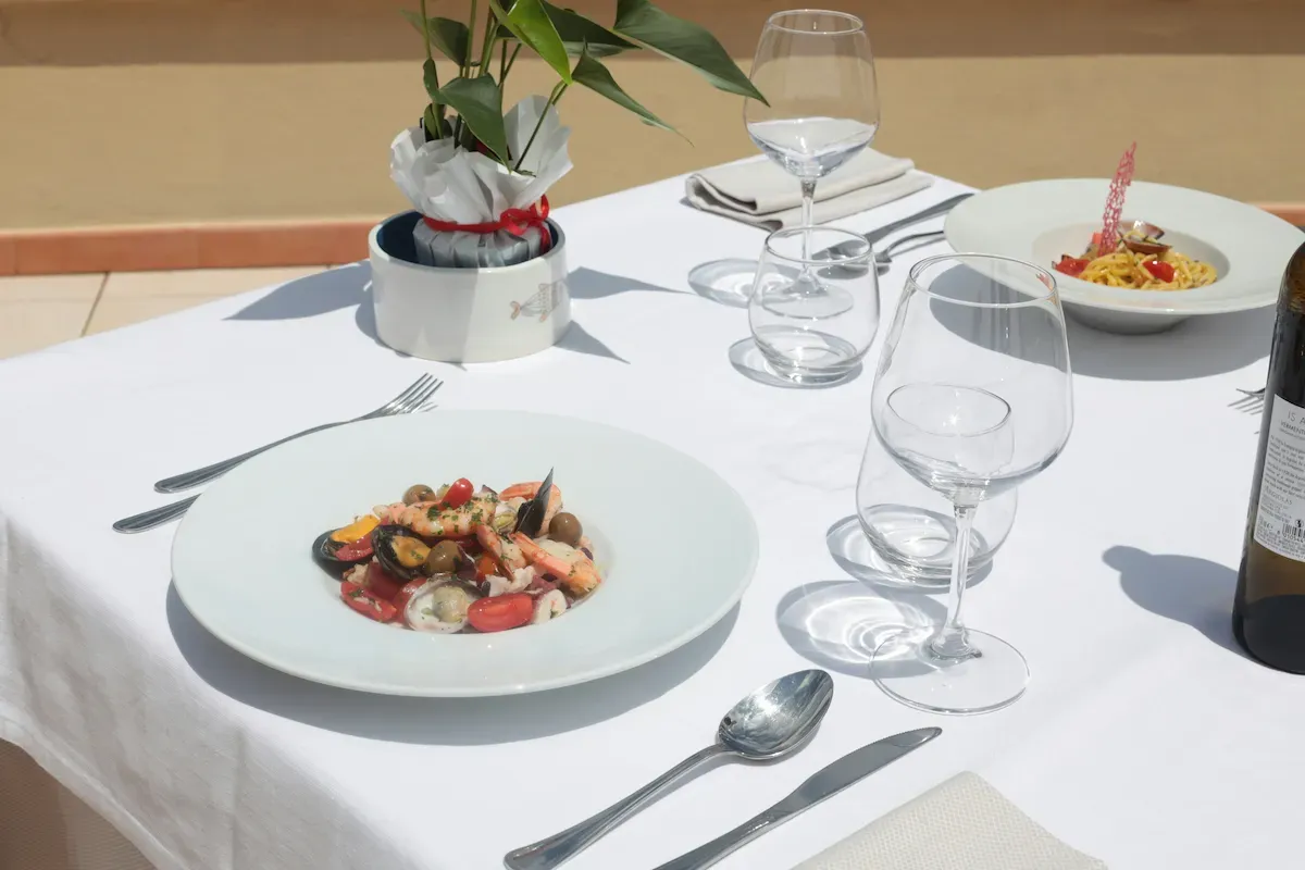 Tavolo con piatti di mare e vino bianco per la prenotazione demo